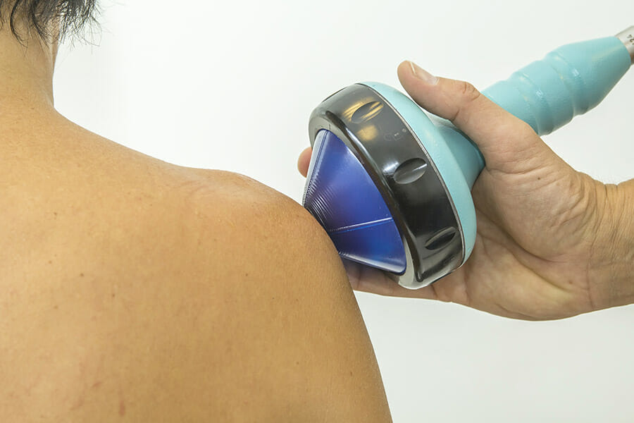 physiotherapist in oakville doing shockwave to a patients shoulder